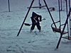 Des enfants jouent dehors, une petite fille pellete la neige près de la balançoire, une femme sort de la maison et se dirige vers la caméra 1963