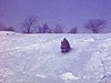 un adolescent descend une colline en mini skis à côté d'une motoneige, il remonte la pente...