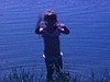 Petite fille se baigne dans un petit lac, elle court dans l’eau puis sort et marche vers sa mère qui est sur une chaise longue au soleil