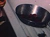 Des framboises dans une passoire dans l’évier de la cuisine, une petite fille en prend et en mange en regardant la caméra